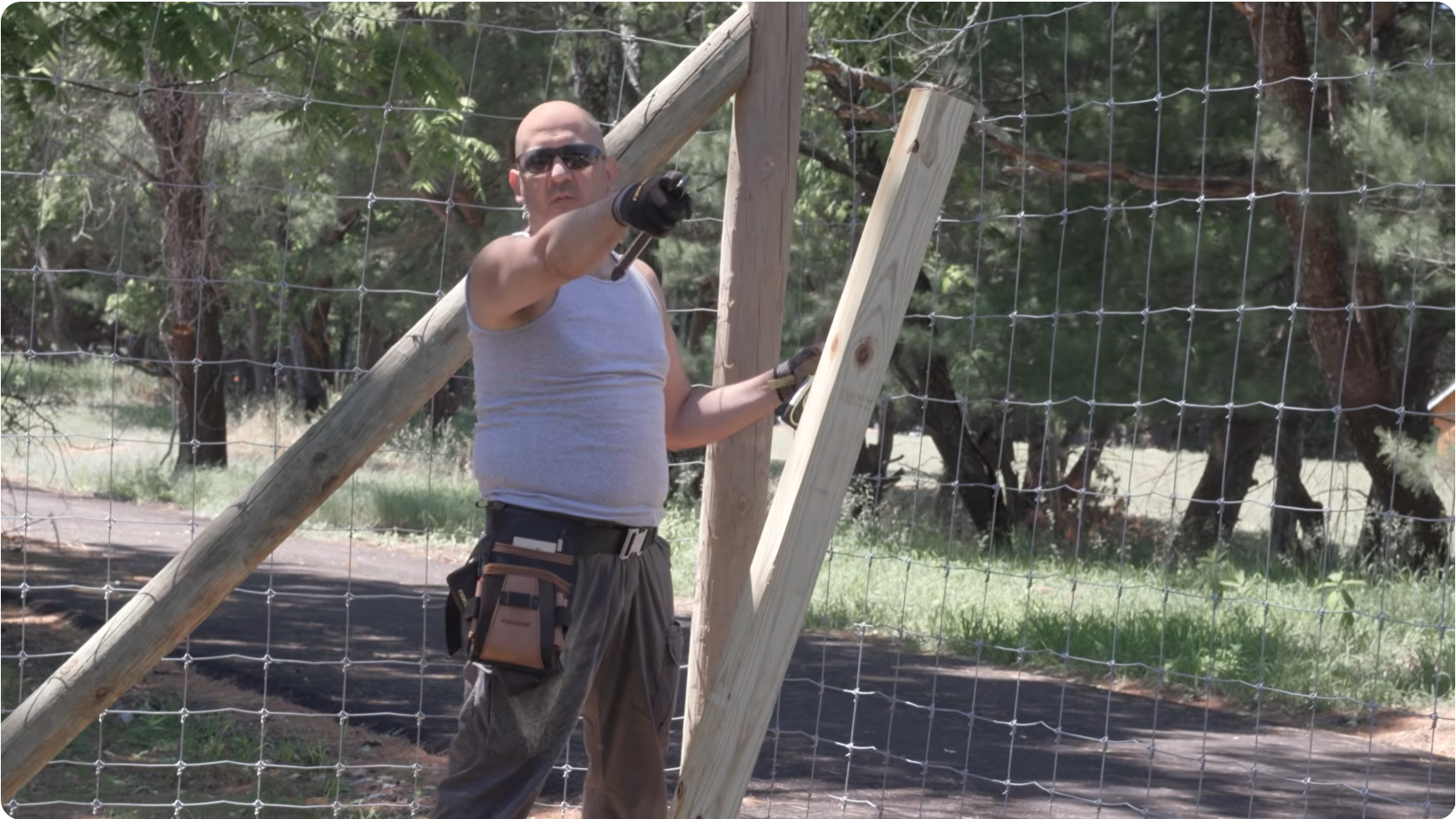 Dennis McClung setting a wooden brace against a wire fence line