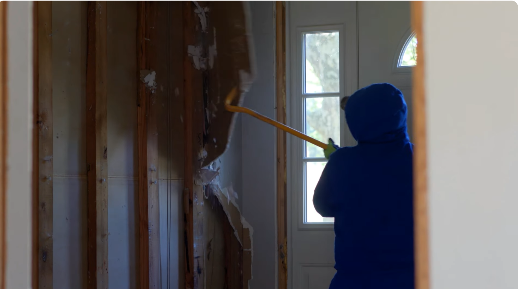 A worker pulling down drywall during a renovation